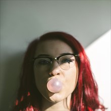 Caucasian woman blowing bubble gum bubble