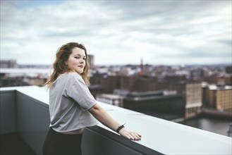 Caucasian woman on urban rooftop admiring cityscape