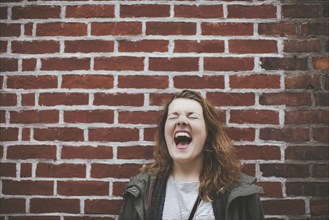 Caucasian woman shouting at brick wall