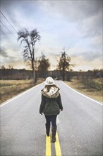 Caucasian woman walking on empty rural road