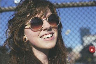 Caucasian woman wearing sunglasses at fence