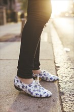 Caucasian woman wearing patterned shoes on city sidewalk