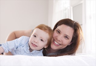 Smiling mother and son hugging on bed