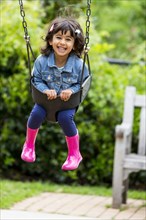 Smiling girl playing in swing at playground