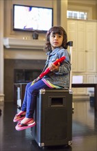 Girl playing toy guitar on amplifier in living room