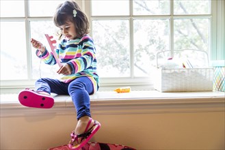 Girl playing with toys in windowsill