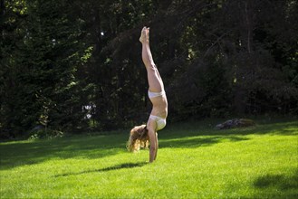 Woman doing handstand in backyard
