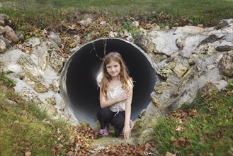 Caucasian girl climbing in storm drain tunnel
