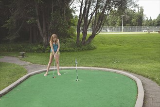 Caucasian girl playing miniature golf