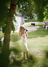 Caucasian girl photographing in backyard