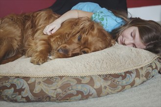 Caucasian girl cuddling dog on cushion