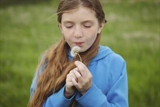 Caucasian girl blowing dandelion outdoors