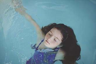 Caucasian girl floating in swimming pool