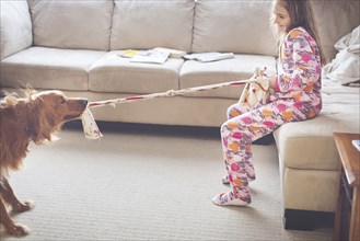 Caucasian girl playing with dog in living room