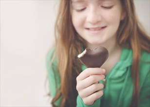 Caucasian girl eating heart-shaped chocolate