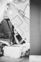Caucasian girl reading in pillow fort
