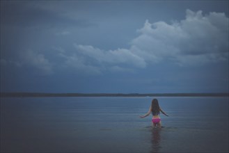 Caucasian girl wading in remote lake