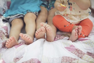 Close up of feet of siblings on blanket