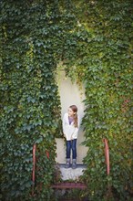Caucasian girl standing at ivy wall