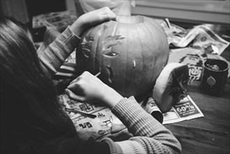 Caucasian girl carving jack-o-lantern pumpkin