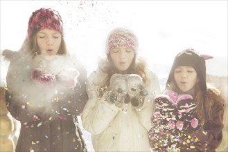 Caucasian girls blowing snow off mittens