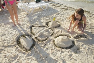 Caucasian teenage girl building sandcastle on beach