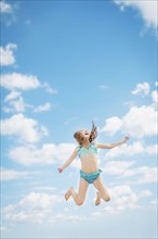 Caucasian girl jumping for joy in blue sky
