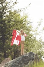 Caucasian girl holding Canadian flag on boulder