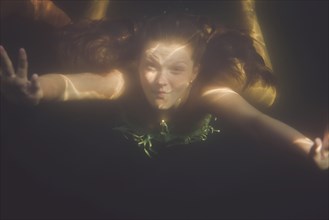 Caucasian teenage girl swimming underwater in lake