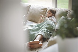 Caucasian girl using cell phone on sofa