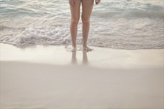Caucasian girl standing in waves on beach
