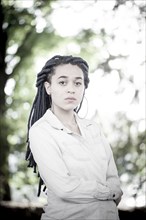 Serious woman with dreadlocks standing outdoors