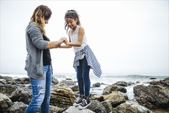 Hispanic mother and daughter exploring tide pools