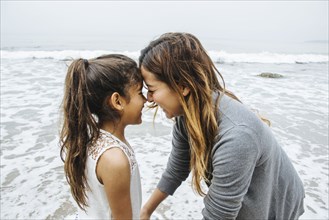 Hispanic mother and daughter standing on beach