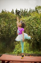 Black girl playing ballerina on picnic table