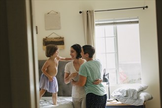 Caucasian family hugging in bedroom