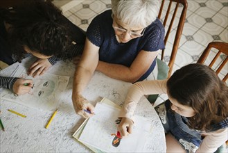 Grandmother and grandchildren drawing at table