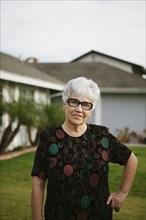 Older woman standing with hands on hips in backyard