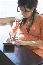 Pregnant woman writing card at table