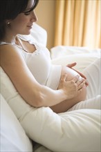 Pregnant woman rubbing her belly on sofa