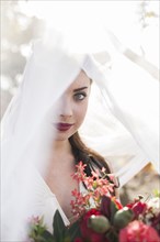Caucasian bride holding bouquet under veil