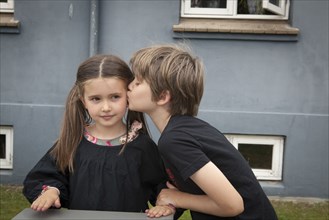 Caucasian boy kissing sister in backyard