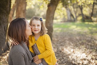 Mother kissing daughter in park