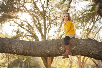 Girl sitting on tree branch in park
