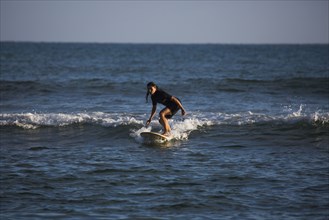 Hispanic woman surfing in ocean