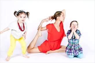 Mother practicing yoga with playful daughters