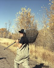 Happy woman carrying fishing net on dirt path