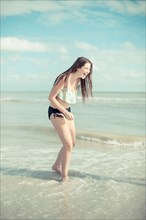Caucasian teenage girl playing in waves on beach