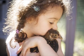 Close up of girl hugging chicken on farm