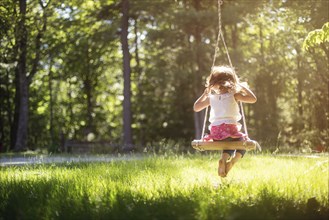 Girl sitting on swing in field